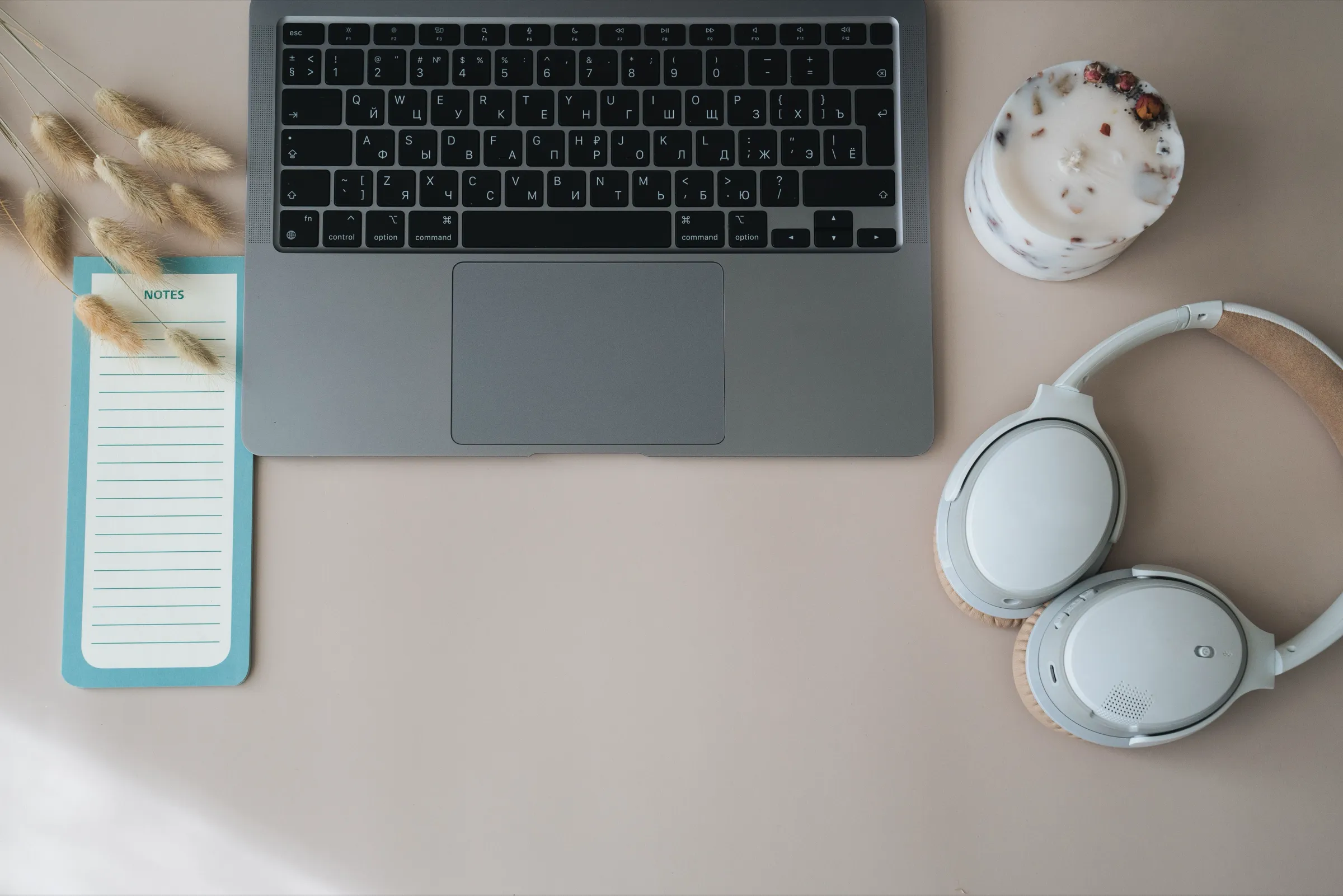 Mesa minimalista com notebook, bloco de notas e fone ao lado