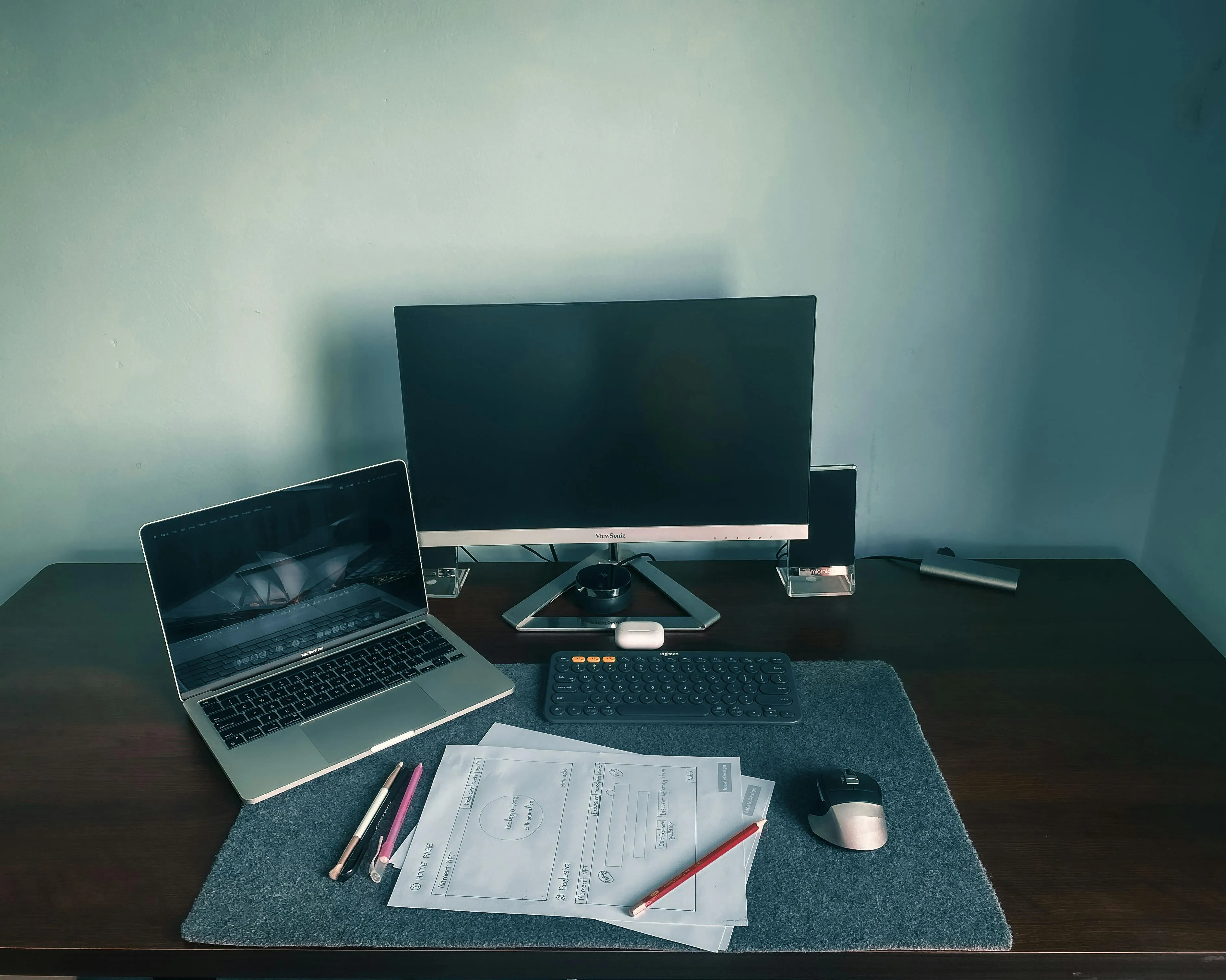 Mesa de home office com notebook, monitor, teclado, mouse e papeis organizados em um setup funcional